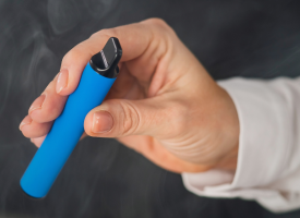 Woman's hand holding a blue disposable vape
